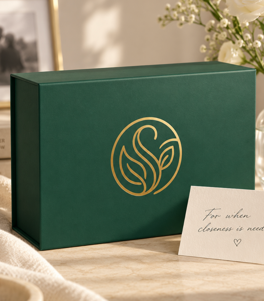 Stay design preview: emerald keepsake box with a gold monogram beside cream flowers and a handwritten card.